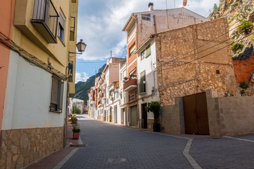 An empty road in the shade of colorful houses and buildings surrounding it under a bright cloudy sky