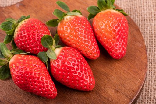 A high angle closeup shot of fresh strawberries on a round wooden desk