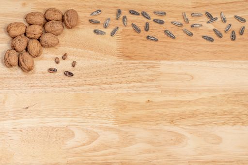 A top view of walnuts, sunflower seeds, and pine nuts on a wooden table