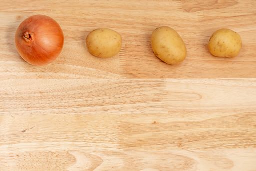 A top view of onion and potatoes on a wooden table