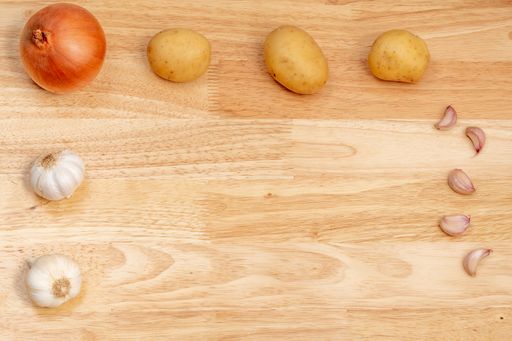 A top view of onion, garlic, and potatoes on a wooden table