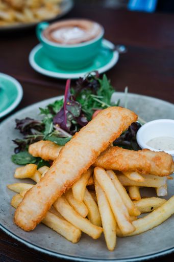 A vertical shot of a plate with fish sticks, french fries, and salad