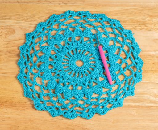 A blue hand-knitted piece and hooks on a wooden surface
