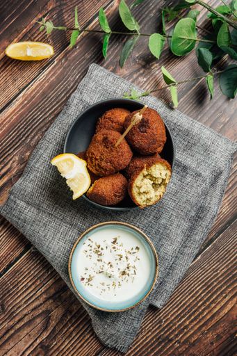 A plate of delicious falafel dish with yogurt sauce on the table
