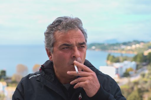 A man smoking a cigarette against the blurred background of the sea, Greece