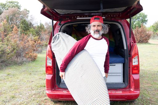Attractive bearded hipster surfer looking at camera holding a board.  sport adventure lifestyle.