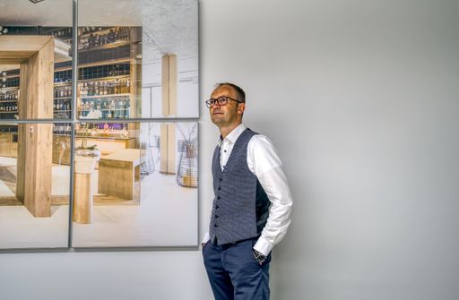 An adult businessman standing near the pictures on a wall in the office