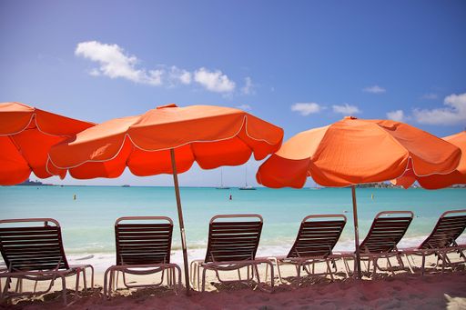 A scenic view of beach chairs with umbrellas on a sandy beach on a sunny day