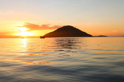 A landscape of the sea with the hill silhouette during the sunset on the background