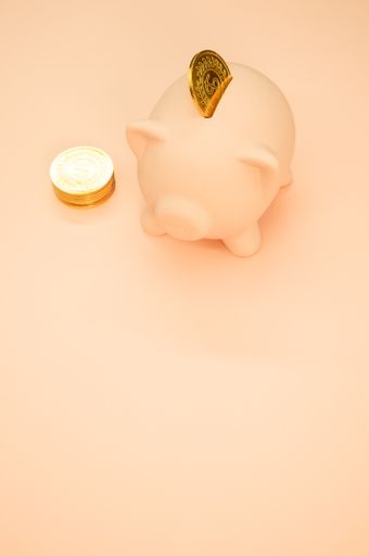 A vertical shot of a piggy bank and coins on an orange background with space for your text - savings and banking concept