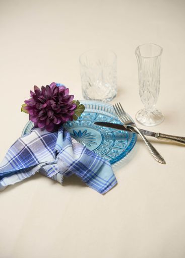 A beautiful table setting with plate, cutlery, glass cups, napkin and flower
