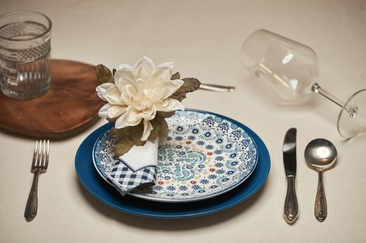 A beautiful table setting with plates, cutlery, glass cups, napkin and flower