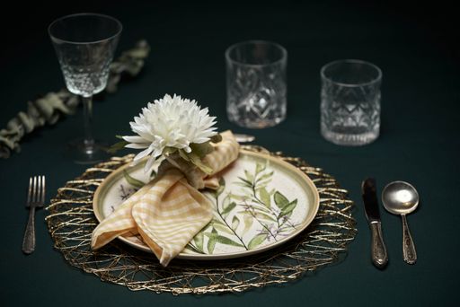 A beautiful table setting with plate, cutlery, glass cups, napkin and flower