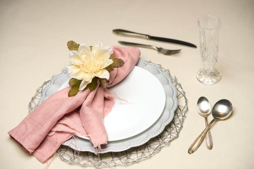 A beautiful table setting with plates, cutlery, glass cups, napkin and flower