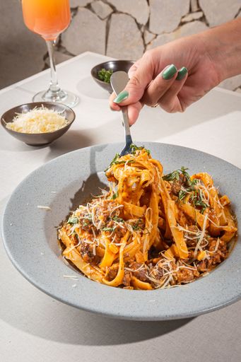 A bowl of delicious fresh pasta with meat, sauce, and cheese on the table