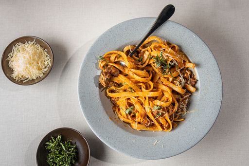 A bowl of delicious fresh pasta with meat, sauce, and cheese on the table