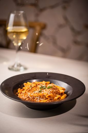 A bowl of delicious penne pasta with cheese and sauce on the table