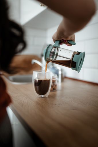 A vertical shot of a barista pouring coffee into the glass