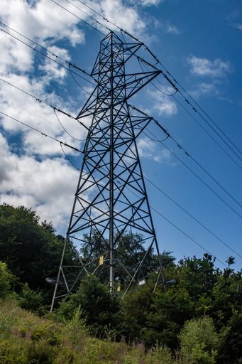 A low angle of an electric pylon on a green hill