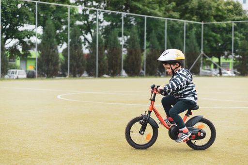 Young Polish Caucasian boy wearing a safety helmet and practicing riding a bike.