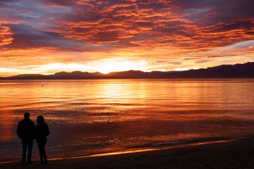 A closeup shot of silhouettes of a couple standing on the seashore at sunset