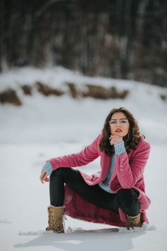 A vertical shot of a young caucasian stylish female posing on a snowy field