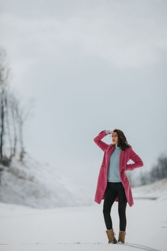 A vertical shot of a young caucasian stylish female posing on a snowy field