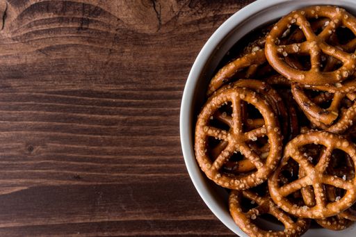 A top view of salty pretzels in the bowl on the wooden table with copy space