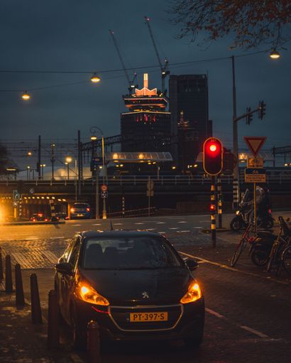 Amsterdam, Netherlands - November 27 2022: A view of the A'dam Toren at night from a street, with a parked car and traffic light.