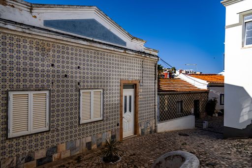 A scenic view of a cobblestone street with houses on a sunny day