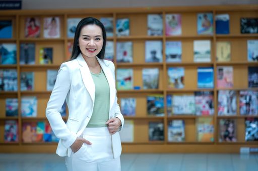 A closeup of a  young Asian female in a white suit  standing and posing with a blurry background