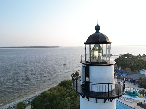 A majestic lighthouse stands proudly atop a rugged cliff overlooking a beautiful body of water