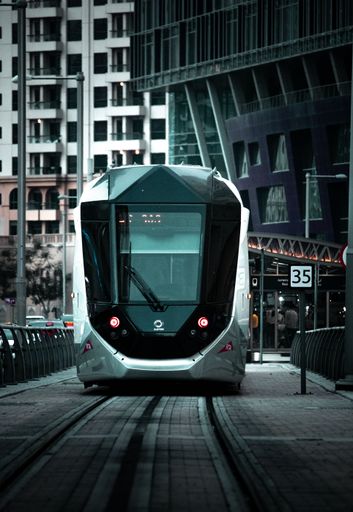 High angle view of a modern, urban train arriving at a station, with tall buildings and cityscape in the background