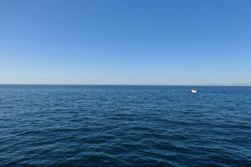 A scenic view of a tranquil bay with a boat floating in the distance