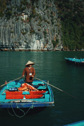 A vertical shot of a man on a boat near the cliff
