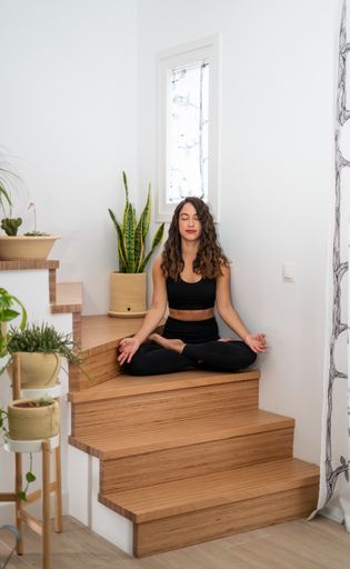 A vertical shot of a white Caucasian woman doing yoga on stairs