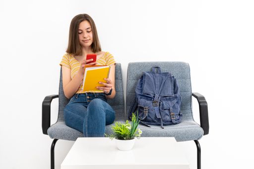 A young female client in the waiting room with a mask taking a photo of her notes on a white background