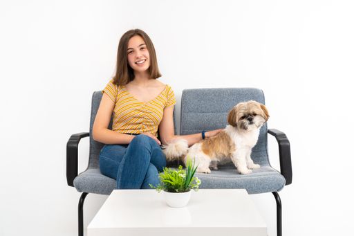 A cheerful young female customer from Spain in the waiting room with her pet on white background