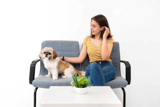 A cheerful young female customer from Spain in the waiting room with her pet on white background