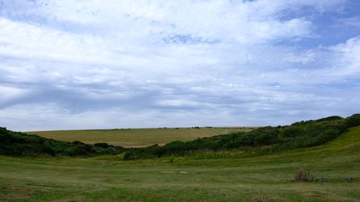 A scenic view of a lush green landscape under a cloudy blue sky