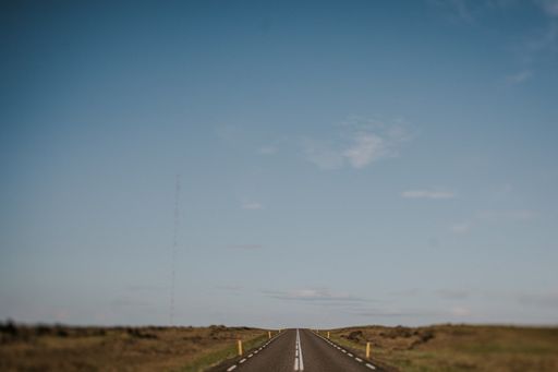 A beautiful shot of an empty road in the middle of a grassy field during daytime