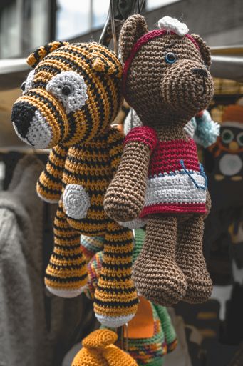A closeup of stuffed toys hanging on the post outside the store