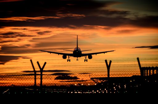 A beautiful shot of a silhouette of a flying airplane beneath golden clouds during sunset