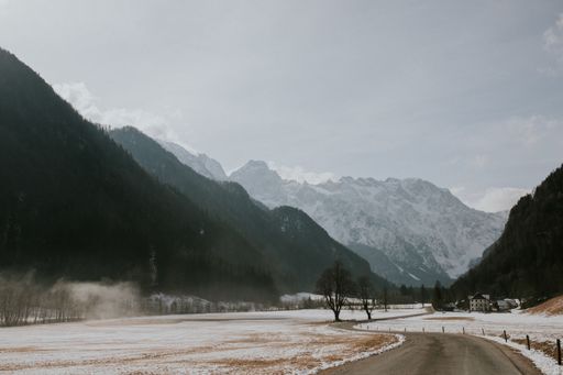 A beautiful scenery of a road surrounded by high rocky mountains under a cloudy sky