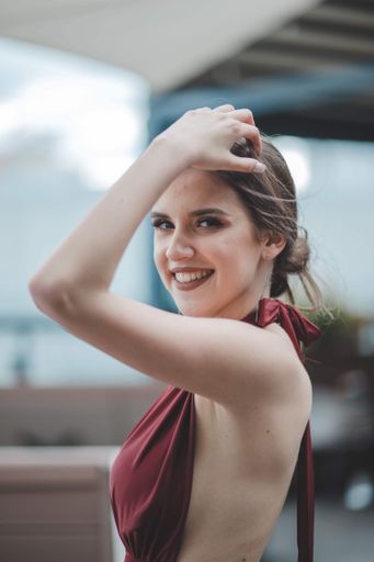 A shallow focus of a young brunette woman wearing a red dress in an outdoor restaurant