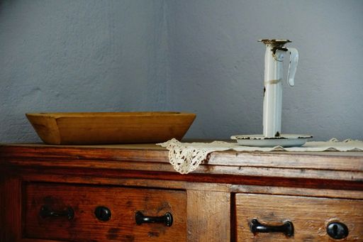 A setting of an old interior with a weathered candleholder with wooden drawers and a wooden plate