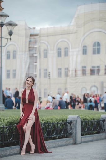 A young attractive Caucasian female wearing a beautiful elegant red dress and walking on a street