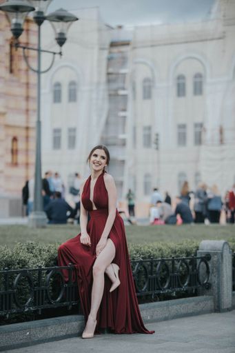 A young attractive Caucasian female wearing a beautiful elegant red dress and walking on a street