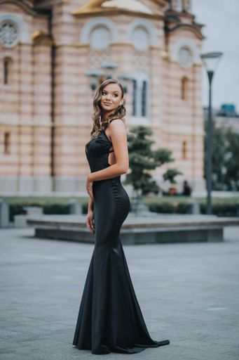 An attractive Caucasian woman wearing an evening dress posing in the street
