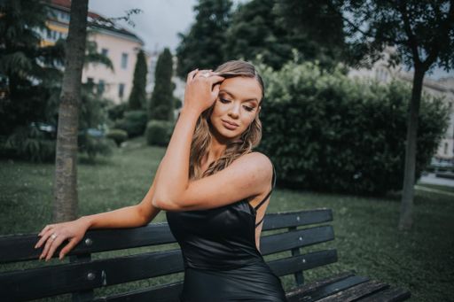 A beautiful sexy Caucasian woman in a black backless gown posing outdoors